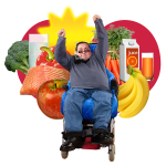 ""A man in a wheelchair with his arms raised and fruit and vegetables around him
